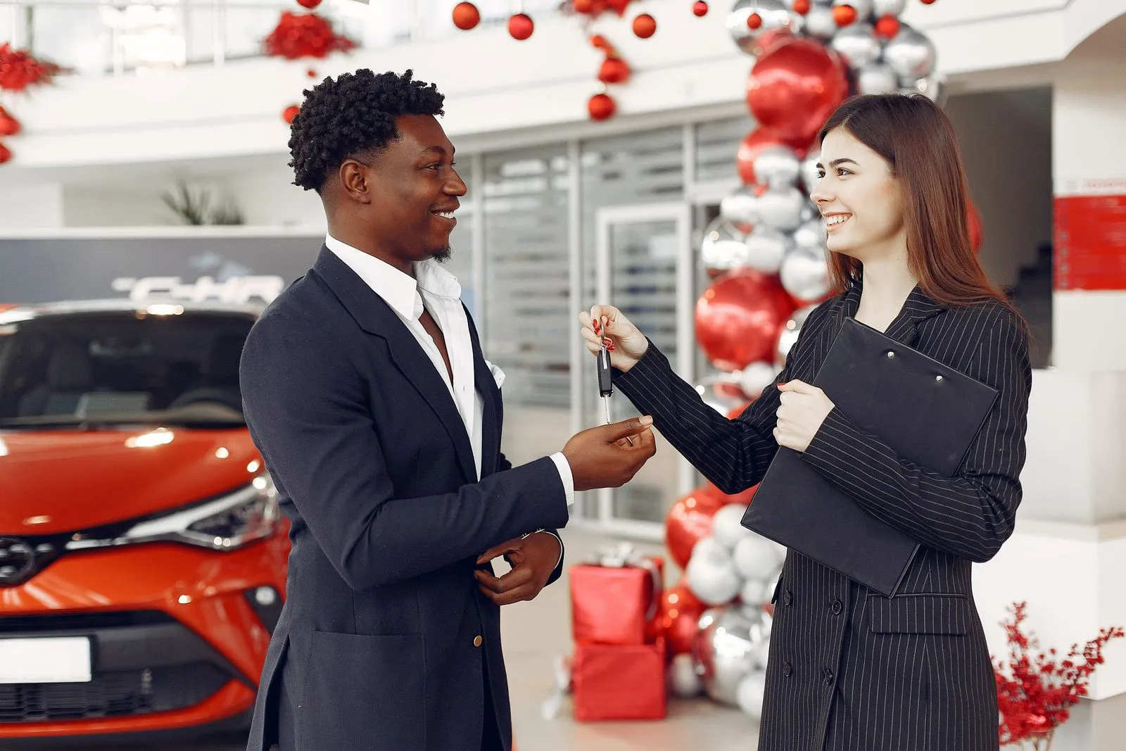 A car dealer handing over a set of car keys to a customer, illustrating a vehicle changing hands