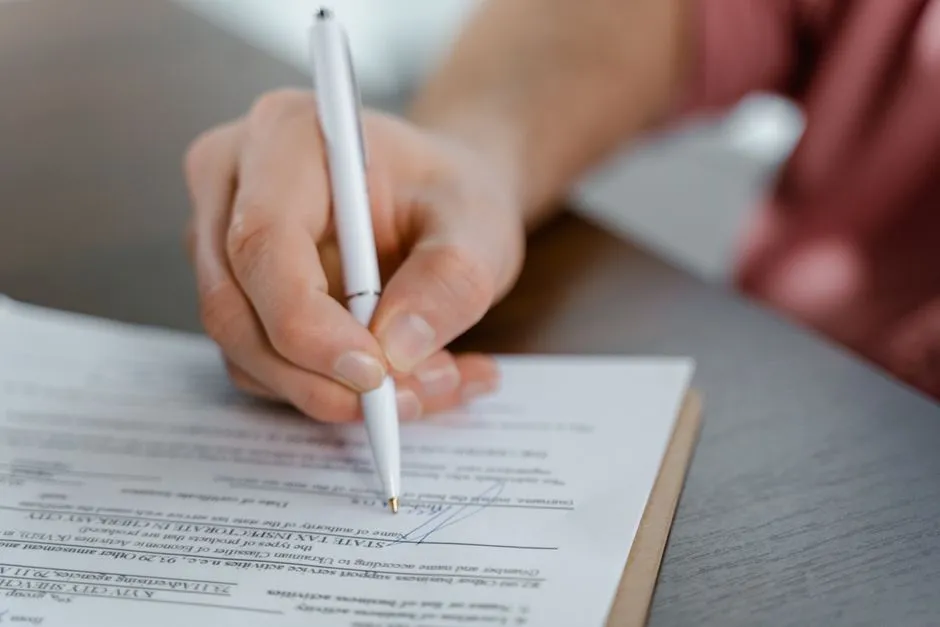 Close-up of a hand writing a signature on an official document